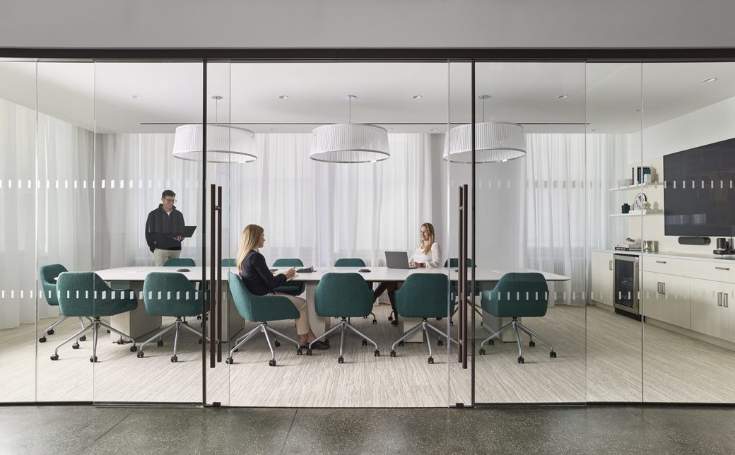 Glass-walled conference room with a large table and seating